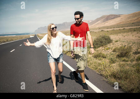 Full length of happy woman talking with man while walking on road Stock Photo