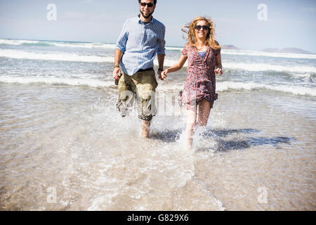 Cheerful couple running in sea on sunny day Stock Photo