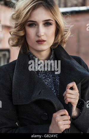 Portrait of attractive young woman wearing long coat outdoors Stock Photo