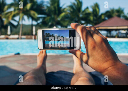 Low section of man photographing swimming pool in tourist resort Stock Photo