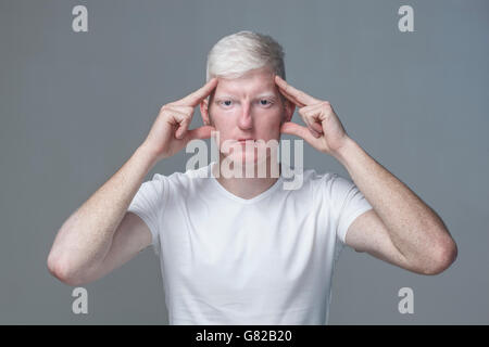 Portrait of young man with head in hands against gray background Stock Photo