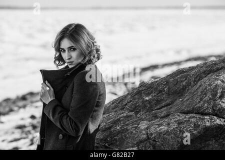 Portrait of beautiful young woman wearing winter coat while standing by rock Stock Photo