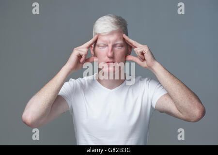 Portrait of young man focusing with closed eyes against gray background Stock Photo