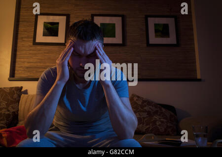 Man suffering from headache while sitting on sofa at home Stock Photo