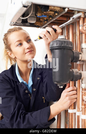 Female Plumber Working On Central Heating Boiler Stock Photo
