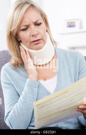 A middle aged woman wearing reading glasses is backlit by the setting ...