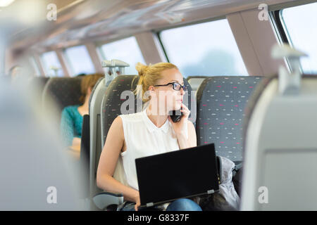 Business woman working while travelling by train. Stock Photo