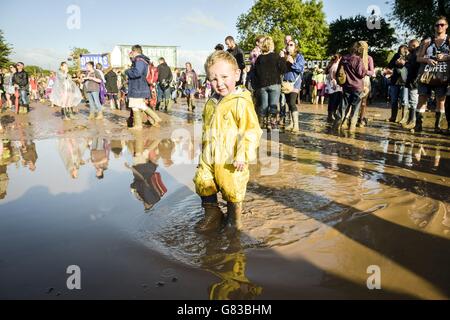 Freddie McKnespie, aged two, from Norwich, who is at his third Glastonbury, plays in puddles at the Glastonbury Festival, at Worthy Farm in Somerset. Stock Photo