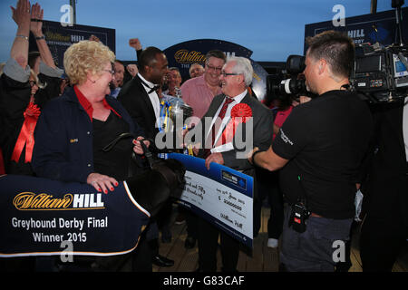 Greyhound Racing - William Hill Derby - Finals - Wimbledon Stadium. Rio Quattro owned and trained by Danny Riordan (2nd right) is presented with the trophy after winning the William Hill Greyhound Derby. Stock Photo