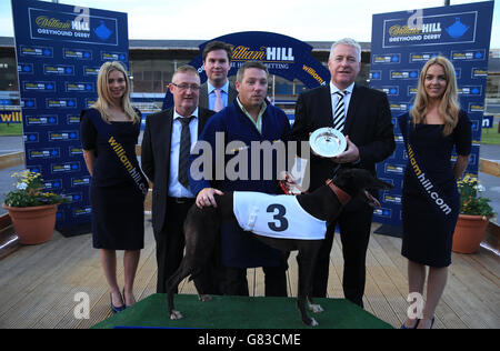 Greyhound Racing - William Hill Derby - Finals - Wimbledon Stadium. Dominio Storm with handler Kevin Ulla (centre) working for trainer Mark Willis after winning The William Hill Derby Plate Final Stock Photo