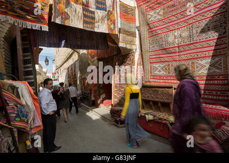 Local residents dash through the rug-lined narrow streets of the Fez Medina in Morocco. Stock Photo