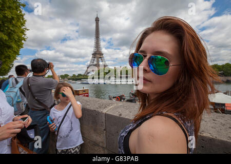 Beautiful girl posing at the Seine River boulevards with Eiffel Tower ( Tour Eiffel ) in background, Paris, France Stock Photo