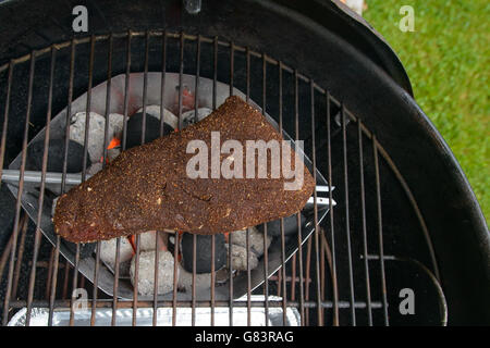 starting to grilling a big piece of beef meat in barbecue Stock Photo