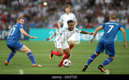 England's Raheem Sterling runs at Iceland's Johann Berg Gudmundsson (right) during the Round of 16 match at Stade de Nice, Nice, France. Stock Photo