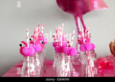 Pink flamingo straws in glass bottles in a row