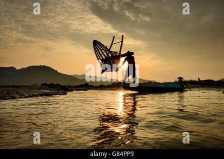 Silhouette of Man throwing fishing basket into Mekong river, Thailand Stock Photo