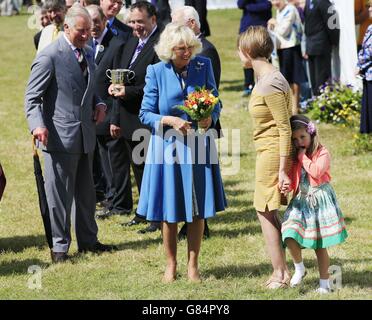 RETRANSMITTING INCLUDING NAME OF YOUNG GIRL Five-year-old Pleasance Allen hides behind her mother after she handed a bouquet of flowers to the Duchess of Cornwall (left) during her visit with the Prince of Wales to Sandringham flower show held on the Royal Estate in Norfolk. Stock Photo