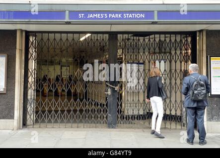 People look at a display showing service information through the gates of a closed St James's Park Underground station in Westminster central London, during strike by Tube workers. Stock Photo