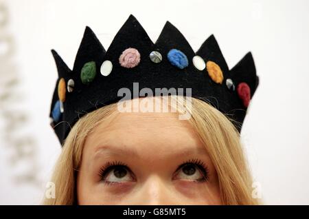 A Christie's employee dons a felt crown made by Stephen Jones and worn by Kate Moss on her first magazine photo shoot during a press preview for the third annual 'Out of the Ordinary' auction hosted by Christie's in South Kensington, London. Stock Photo