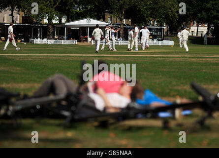 Spectators bask in the afternoon sun as a Kew Cricket Club's Sunday XIside take on Lord Gnome's at the Kew Cricket Club Stock Photo