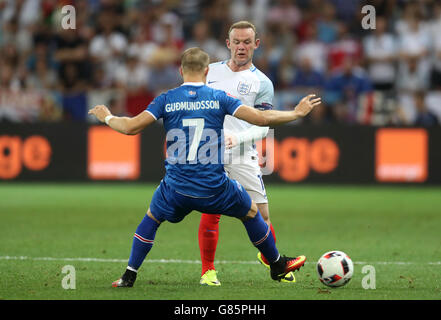 Iceland's Johann Berg Gudmundsson (left) and England's Wayne Rooney battle for the ball during the Round of 16 match at Stade de Nice, Nice, France. Stock Photo