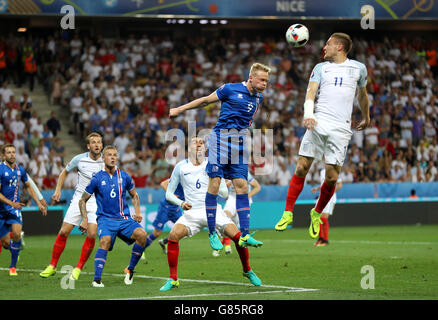 Iceland's Kolbeinn Sigthorsson (centre) heads the ball clear from England's Jamie Vardy during the Round of 16 match at Stade de Nice, Nice, France. Stock Photo
