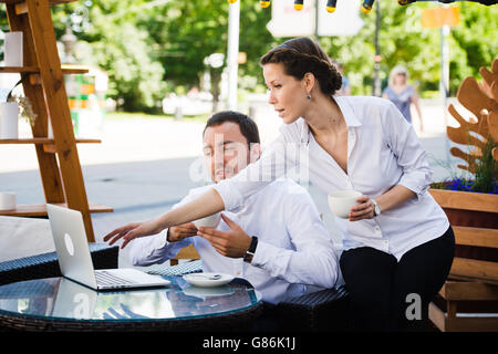 man and woman working on laptop at outdoors cafe during the break Stock Photo