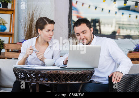 Businessman and businesswoman working outdoor at street cafe during the lunch Stock Photo