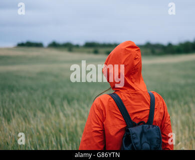 Rear view of woman in raincoat standing in field Stock Photo