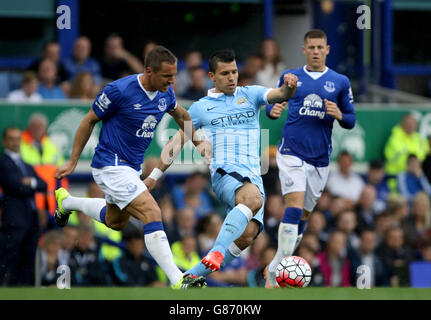 Manchester City's Sergio Aguero (centre) and Everton's Phil Jagielka (left) battle for the ball during the Barclays Premier League match at Goodison Park, Liverpool. Stock Photo