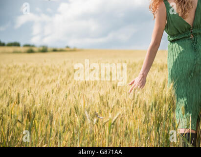 Woman walking through wheat field, Bulgaria Stock Photo