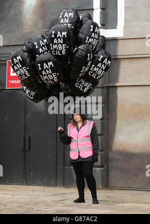 An exhibition guide holding balloons, during the press day for the artist Banksy's biggest show to date, entitled 'Dismaland', at Tropicana in Weston-super-Mare, Somerset. Stock Photo