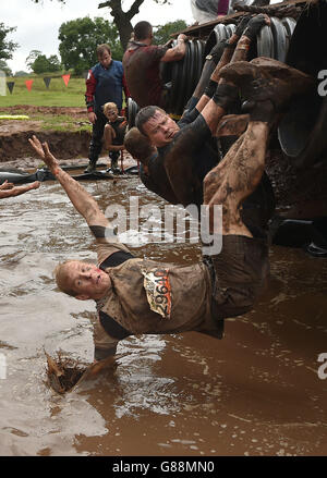 A participant falls backwards into a pool of muddy water during Tough Mudder North West at the Cholmondeley Estate in Malpas, Cheshire. Stock Photo