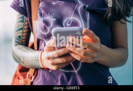 Woman with tattoos texting on mobile phone Stock Photo