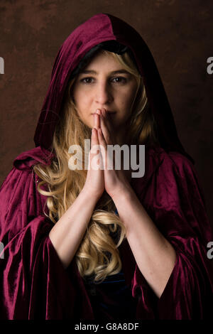 Fantasy makeover photography : a young woman model  wearing a blonde wig and a purple cape posing as a 'earth goddess' or priestess in a 'game of thrones' inspired session Stock Photo