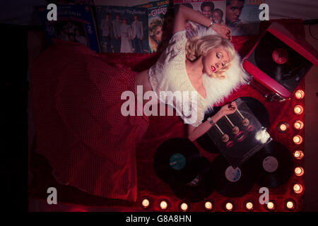 Retro 50's chic: a young blonde woman girl lying down on the floor listening to analogue vinyl music records LPs albums scattered on the floor at home UK Stock Photo