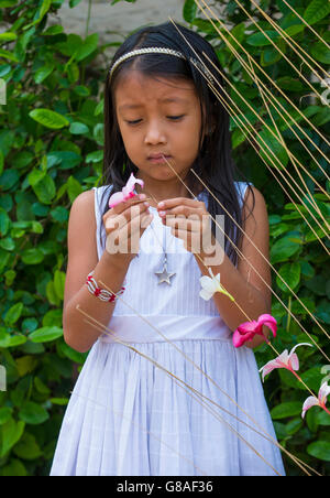 A Salvadoran girl decorates palm fronds with flowers during the Flower & Palm Festival in Panchimalco, El Salvador Stock Photo