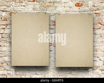 Close-up of two blank brown canvas frames hanged by pegs against old weathered brick wall background Stock Photo