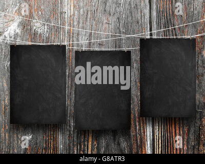 Close-up of three blank blackboard frames hanged by pegs against dark wooden boards background Stock Photo