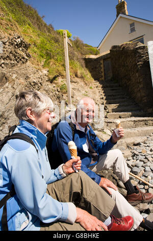 UK, Wales, Ceredigion, Llangrannog, beach, senior couple eating ice cream at bottom of cliff path Stock Photo