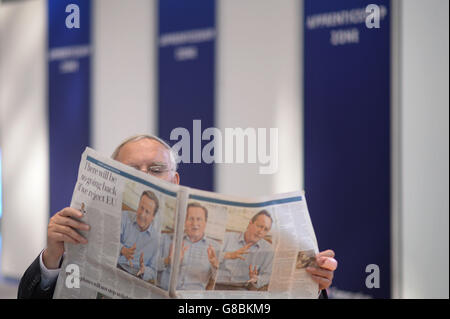 A Conservative Party member reads a newspaper, as party members gather in Manchester for the start of their annual conference which begins today. Stock Photo