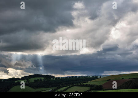 Near Knighton, Powys, UK, on the border between England and Wales. Beams of sunlight breaking through dark stormclouds Stock Photo