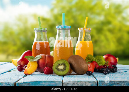 Fresh glasses of juice with fruit mix placed on wooden planks. blur garden on background. Concept of healthy drinks, antioxidant Stock Photo
