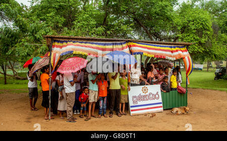 People holding umbrellas up waiting in a rain shelter at a park in Sri Lanka. Stock Photo