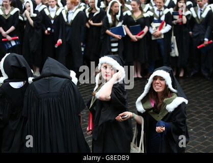 University of Edinburgh students shelter from the rain as they have official photographs taken after their graduation ceremony at the Usher Hall in Edinburgh. Stock Photo