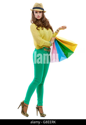 Colourful shopping vibes. Full length portrait of brunette woman in hat and bright clothes with colorful shopping bags posing against white background Stock Photo