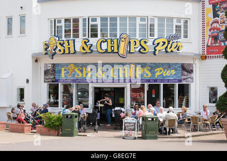 A fish and chip shop at Clacton Pier UK with people eating outside at tables Stock Photo