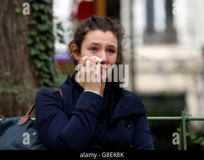 A lady becomes emotional after looking at the floral tributes and candles opposite the Bataclan theatre in Paris, after terror attacks killed at least 129 people in the city on Friday. Stock Photo