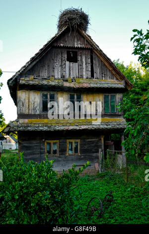 Derelict raditional wooden house with a stork nest on the roof in Cigoc, Croatia Stock Photo