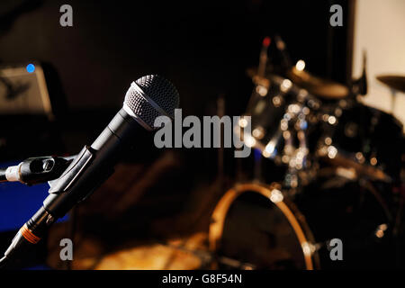 Vocal microphone with stand on the stage with blurred drum set in the background Stock Photo